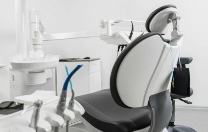 Zahnarztpraxisraum mit Zahnarztstuhl, Behandlungsgeräten und einer Lampe zur Ausleuchtung des Patientenbereichs.