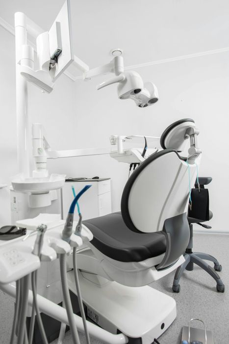 Zahnarztpraxisraum mit Zahnarztstuhl, Behandlungsgeräten und einer Lampe zur Ausleuchtung des Patientenbereichs.