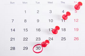 Einen Kalender mit daran angehefteten roten Druckknöpfen
